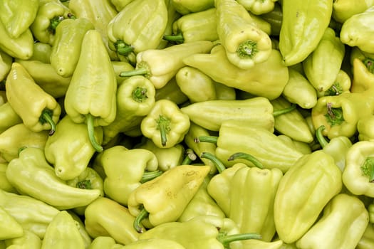 Heap of pointed sweet white bell peppers displayed on food market, closeup detail.