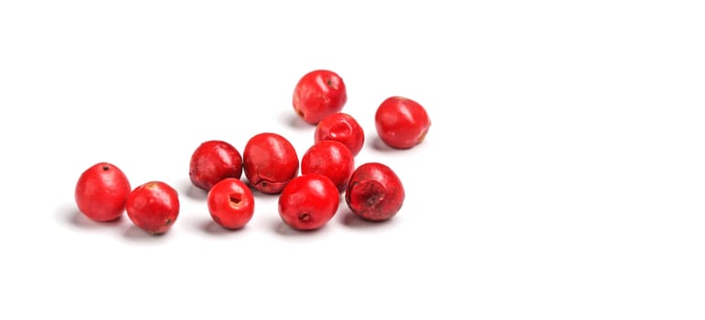 Red or pink peppercorns on board, closeup photo isolated with white background.