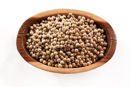 Dried white pepper corns in small wooden bowl - view form above isolated on white background.