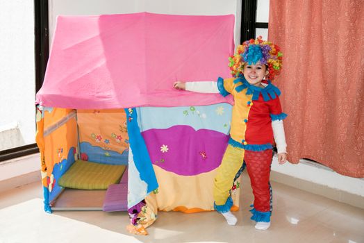 Funny little girl in multicolored clown wig costume looking at the camera.