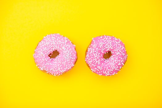 Bright pink delicious donuts on a yellow background