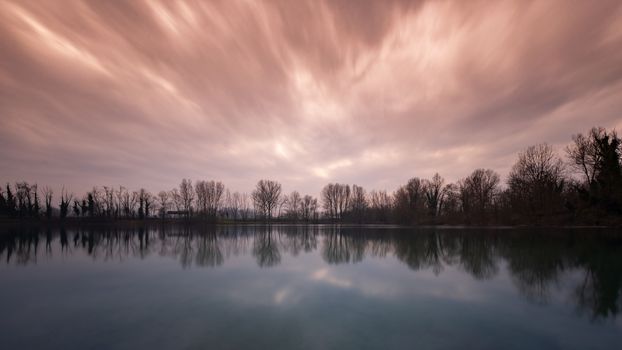 A red and cloudy sky reflected in the water of a lake at sunset time, natural landscape