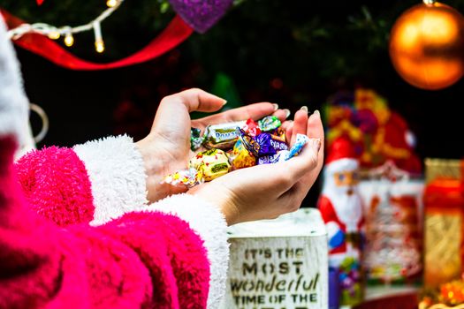 Hands holding candies in front of Christmas tree. Unpacking Christmas gifts isolated.