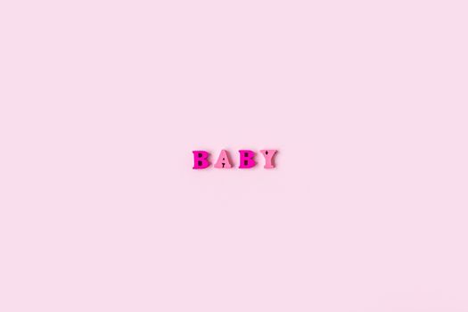 The word BABY is made of wooden letters on a pale pink background. Banner design. Baby shower concept. Photo of minimal background with beeautiful decor and place for text isolated pink background.
