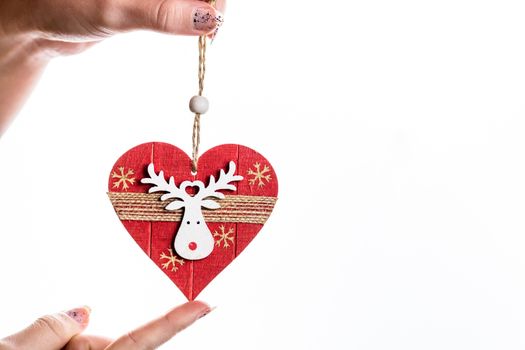 Hand holding heart shaped Christmas decoration isolated on white.