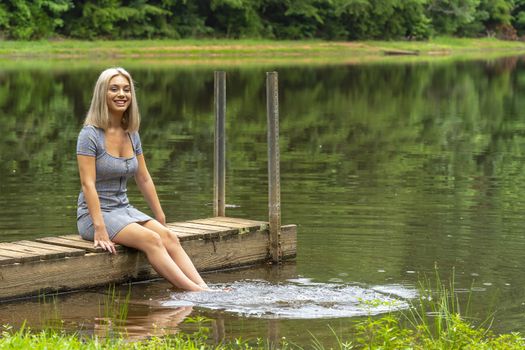 A gorgeous young blonde model poses outdoors in a field of sunflowers while enjoying a summers day