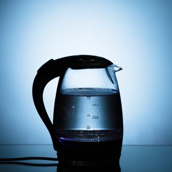 electric glass kettle on blue background