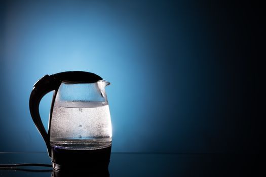 electric glass kettle on blue background