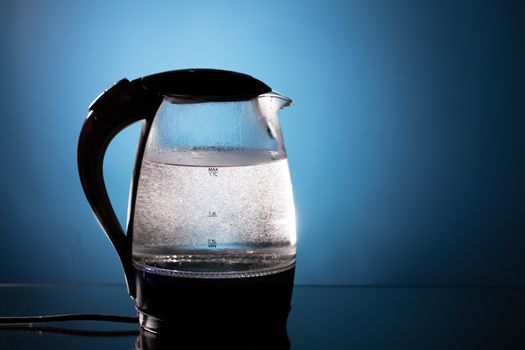 electric glass kettle on blue background