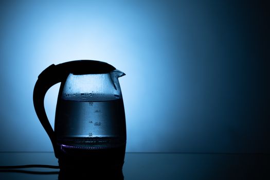 electric glass tea kettle on blue background