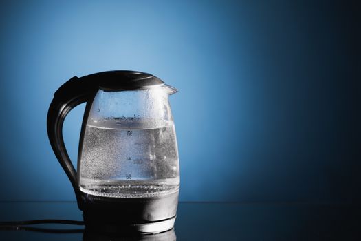 electric glass kettle on blue background