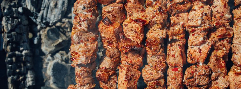 grilled barbecue meat on skewers and charcoals, top view 