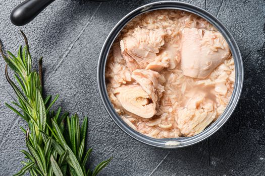 Conserved tuna open can with fresh herbs garlic and lemon ingredients for preservs top view close up.