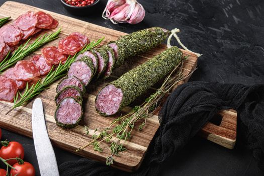 Spanish fuet salami sausage slices on black textured background.
