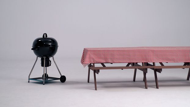 Wood table with red napkin cloth and black BBQ stove and white background in studio.