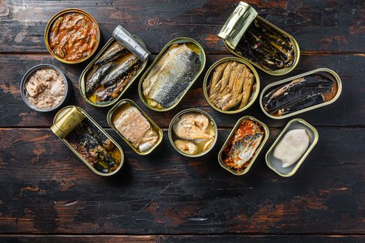 opened cans conserve with Saury, mackerel, sprats, sardines, pilchard, squid, tuna over wood table top view.