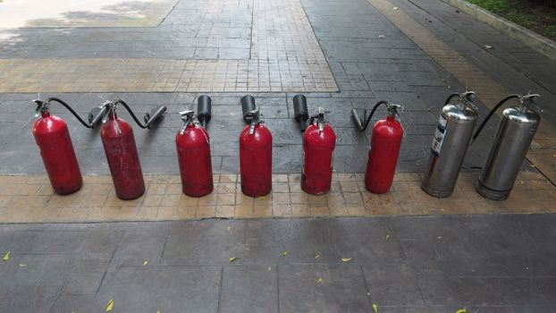 Red and silver color of fire extinguisher tank prepaired on the floor for emergency case.