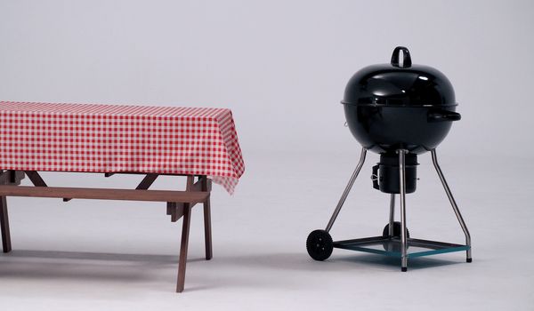 Wood table with red napkin cloth and black BBQ stove and white background in studio.