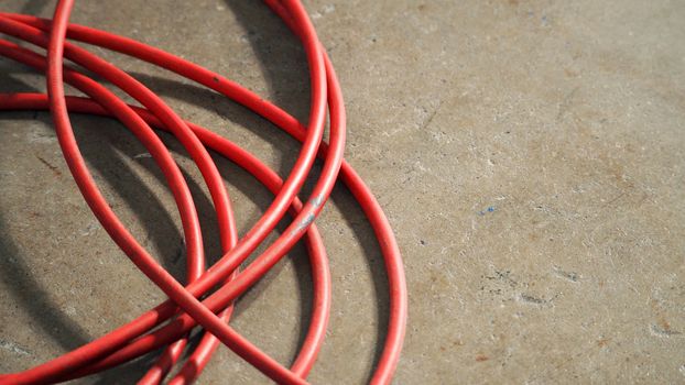 Red color electric power wire cable mess on dirty studio cement floor.