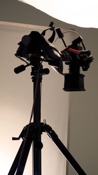 Camera and tripod with light soft box in studio production and low angle view.
