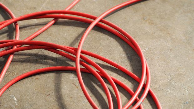 Red color electric power wire cable mess on dirty studio cement floor.