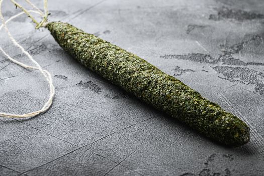 Spanish dry salami sausage fuet in herbs on grey textured background.