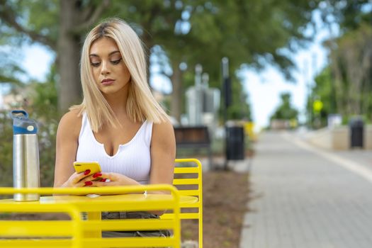 A gorgeous young blonde model poses outdoors while enjoying a summers day