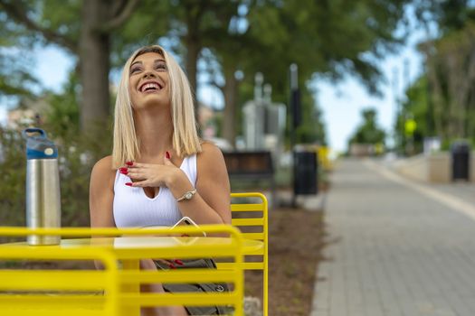 A gorgeous young blonde model poses outdoors while enjoying a summers day