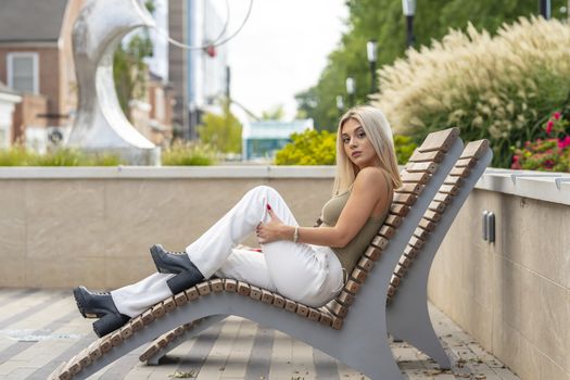 A gorgeous young blonde model poses outdoors while enjoying a summers day