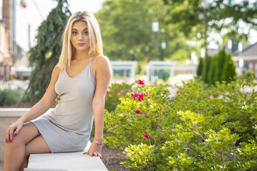 A gorgeous young blonde model poses outdoors while enjoying a summers day