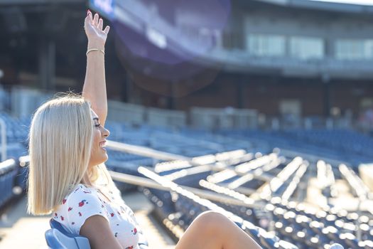 A gorgeous young blonde model poses outdoors while enjoying a summers day at a stadium before a game