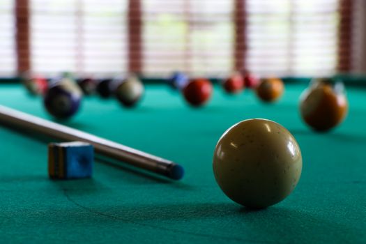 A white cue ball and stick with chalk block on green felt surface of a pool table, South Africa