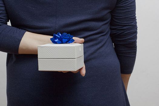 Woman with a gift behind her back on a white background