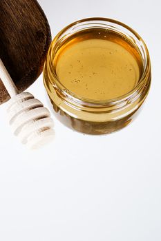 Glass bowl with honey and a wooden dipper on white background