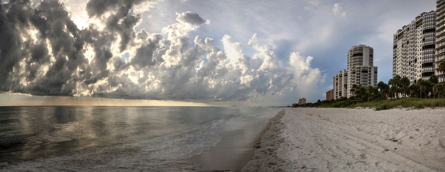 Panoramic Sun peeks through the clouds over the ocean at sunset in Naples, Florida