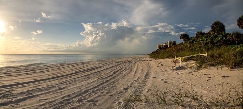 Panoramic Sun peeks through the clouds over the ocean at sunset in Naples, Florida