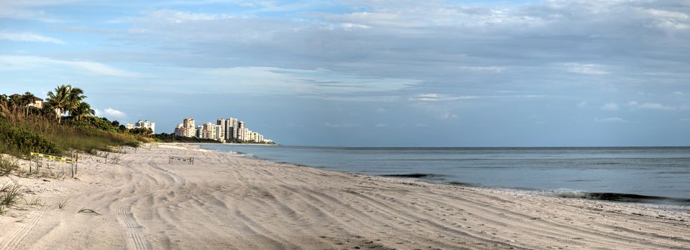 Panoramic Sun peeks through the clouds over the ocean at sunset in Naples, Florida