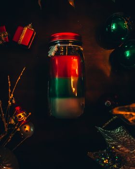 A Red Green and White Christmas Candle Surrounded by Various Holiday Props