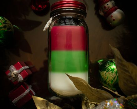 A Red Green and White Christmas Candle Surrounded by Various Holiday Props