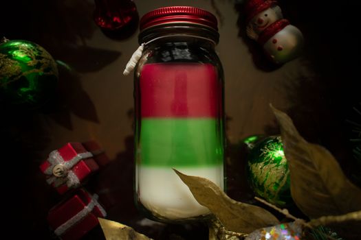 A Red Green and White Christmas Candle Surrounded by Various Holiday Props