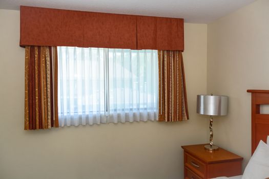 Bedroom window with the curtains and bedside table in the corner of the room
