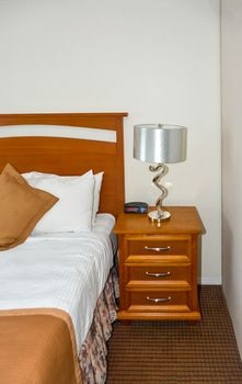 Silver lamp and radio watch on bedside table beside the bed