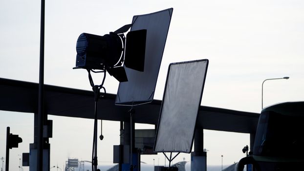 Big LED spotlight and tripod equipment for video or movie production at outdoor location.
