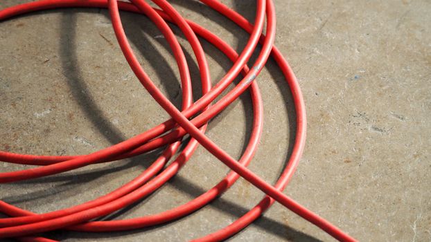 Red color electric power wire cable mess on dirty studio cement floor.