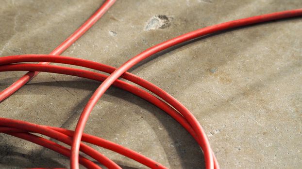 Red color electric power wire cable mess on dirty studio cement floor.