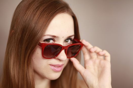 Girl in glasses. Girl portrait in red glasses. Beautiful young curious woman. Woman watching.