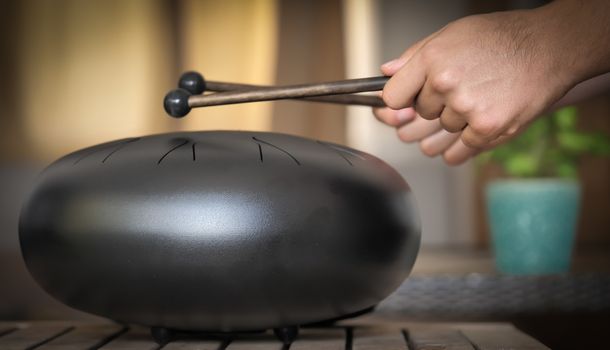 Steel tongue drum rare music playing instrument, made from propane tank and also known as tank drum or hank drum similar to Pantam. Selective focus and motion blur.