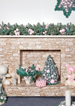 New Years holiday, on and near a stone beige fireplace - gifts, decorative Christmas trees, toys, balls and fir branches in green pearl shades, an image with copy space.