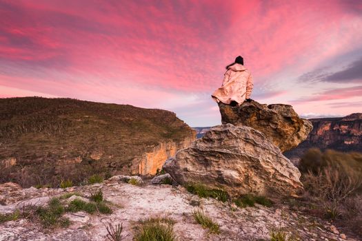 Woman with the best views, sitting on a rock overlooking the escarpment cliffs and valleys watching the sunset.