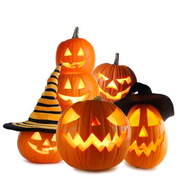 Heap of Jack O Lantern Halloween pumpkins with various different designs and witches hat isolated on white background